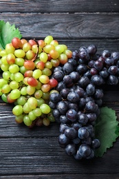 Photo of Different fresh ripe juicy grapes on wooden table
