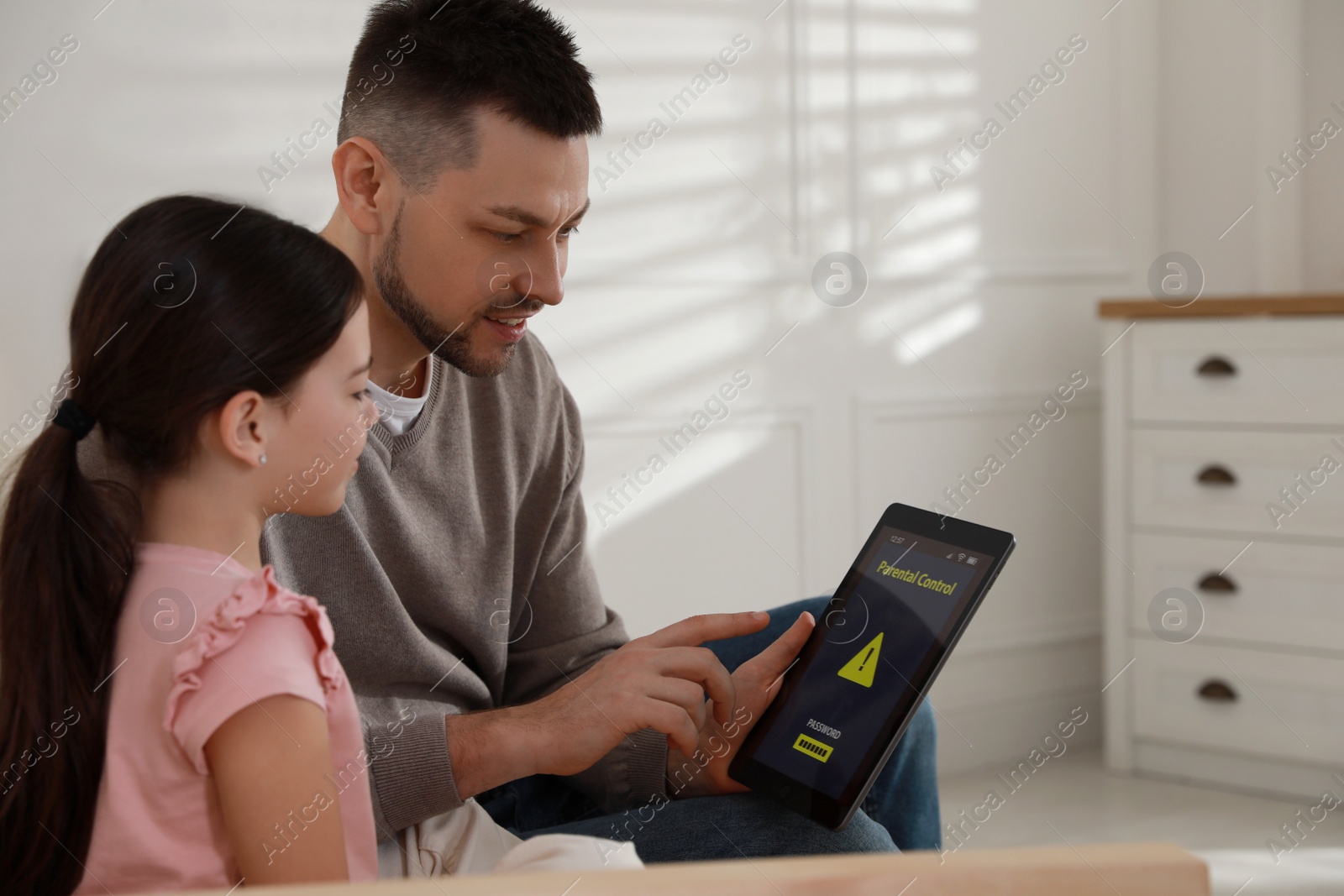 Photo of Dad installing parental control on tablet at home. Child safety
