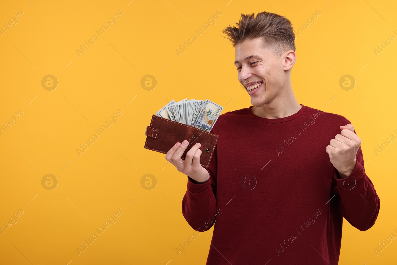 Photo of Happy man with money and wallet on yellow background. Space for text