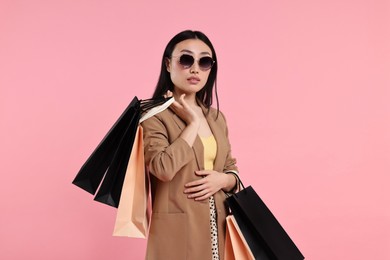 Photo of Beautiful woman with shopping bags on pink background