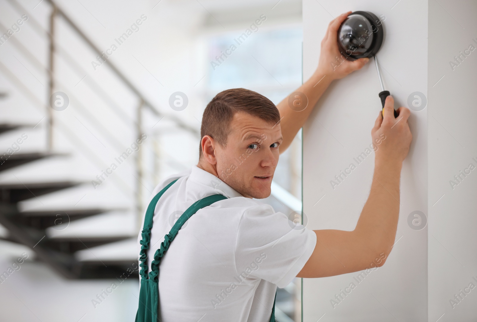 Photo of Technician installing CCTV camera on wall indoors