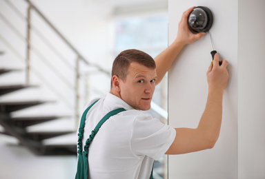 Photo of Technician installing CCTV camera on wall indoors