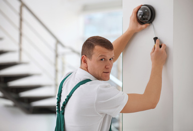 Technician installing CCTV camera on wall indoors