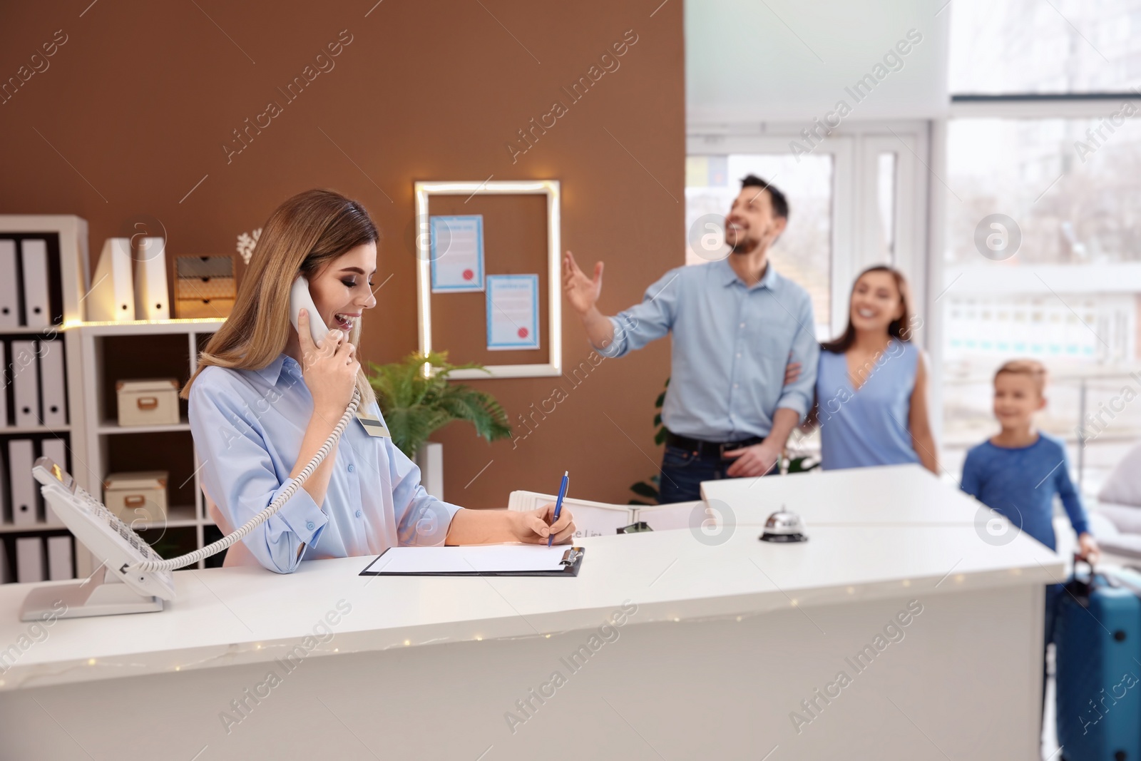 Photo of Female receptionist talking on phone at hotel check-in counter