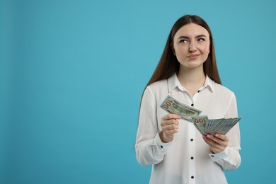 Photo of Woman with dollar banknotes on light blue background, space for text