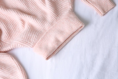 Photo of Pink warm sweater on white crumpled fabric, top view