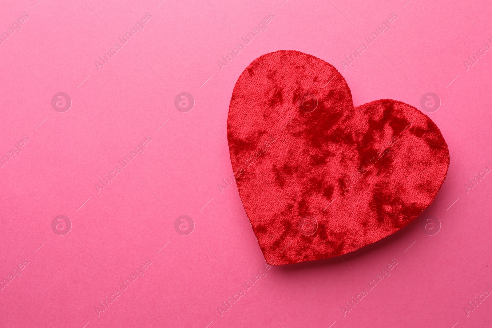 Photo of Red textile heart on pink background, top view. Space for text