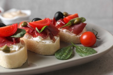 Photo of Delicious sandwiches with bresaola, cream cheese, olives and tomato on table, closeup