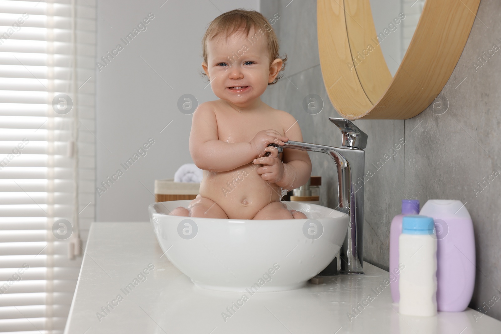 Photo of Cute little baby bathing in sink indoors