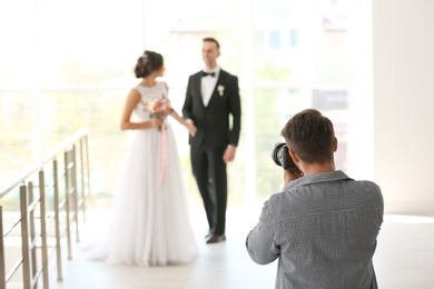 Photo of Professional photographer taking photo of wedding couple in studio