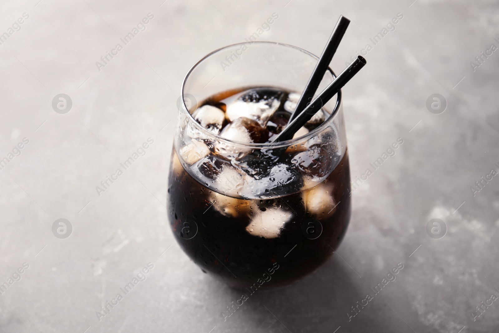 Photo of Glass of refreshing cola with ice on grey background