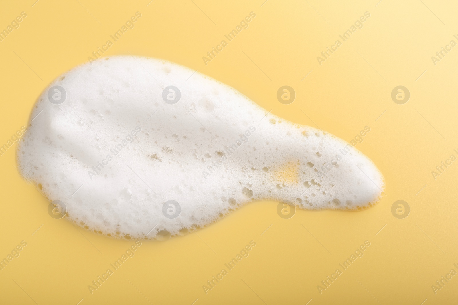 Photo of Sample of fluffy foam on yellow background, top view