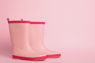 Photo of Pair of rubber boots on pink background. Space for text