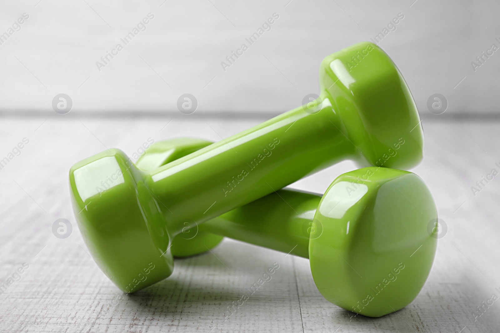 Photo of Bright dumbbells on wooden floor. Home fitness