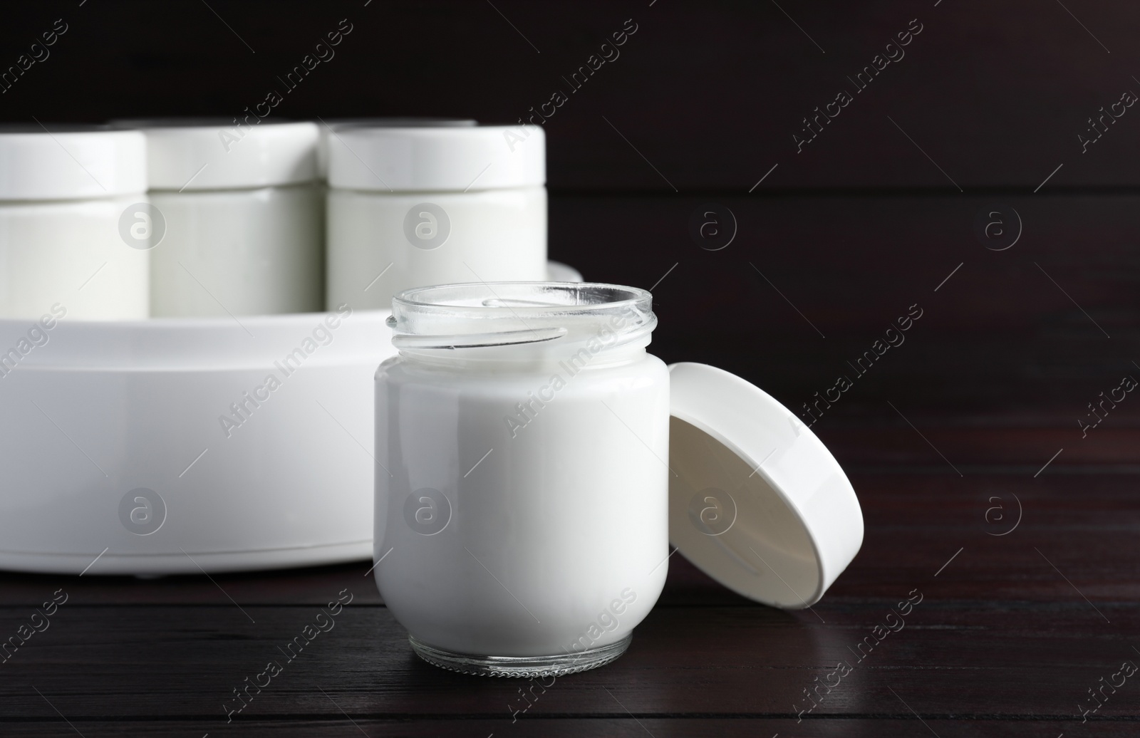 Photo of Glass jar with tasty yogurt on wooden table