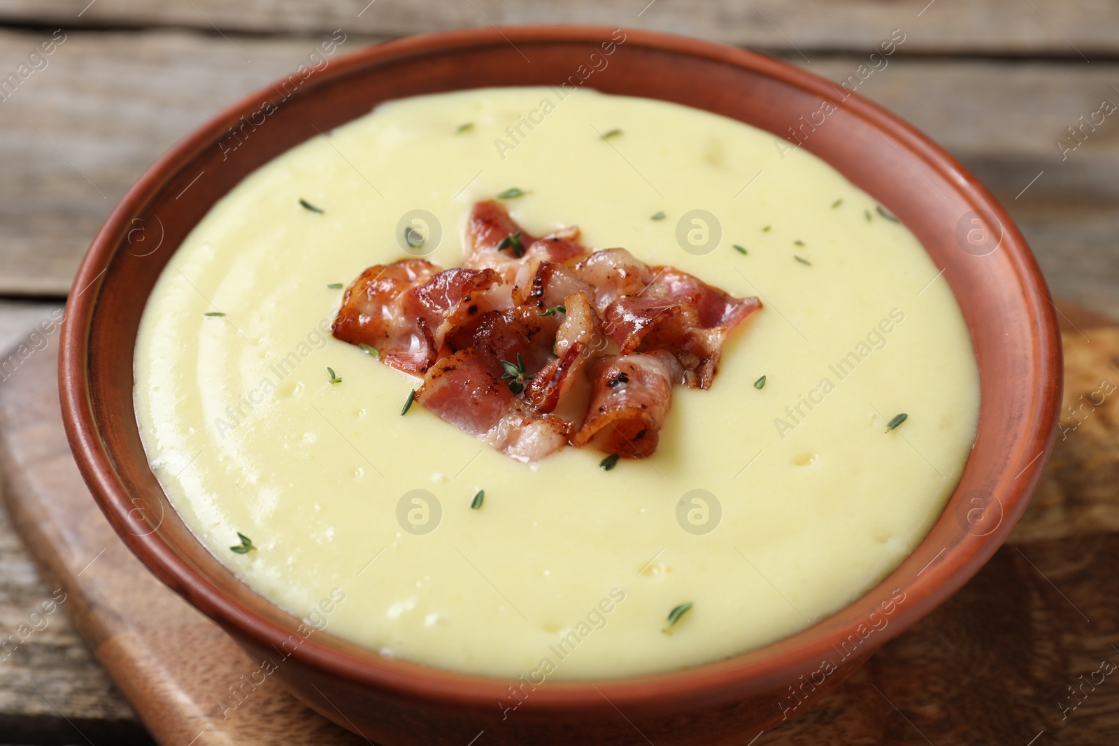 Photo of Tasty potato soup with bacon and rosemary in bowl on table, closeup