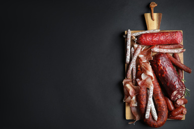 Different types of sausages served on black background, top view. Space for text