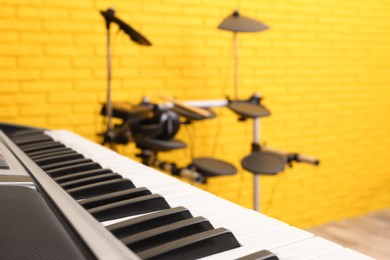 Photo of Musical instruments near yellow wall indoors, focus on synthesizer. Band practice