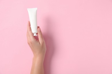 Woman with tube of hand cream on pink background, top view. Space for text