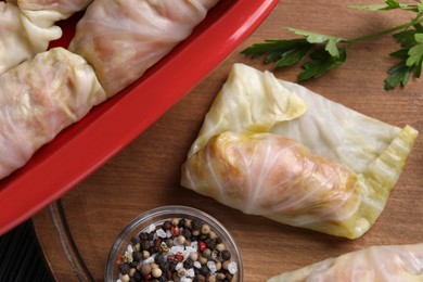 Uncooked stuffed cabbage rolls on wooden board, flat lay