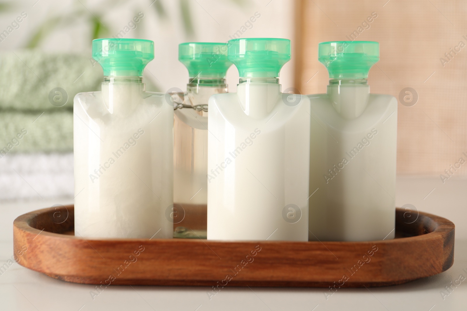 Photo of Mini bottles of cosmetic products on white table against blurred background, closeup