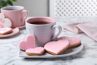 Photo of Delicious heart shaped cookies and cup of tea on white marble table