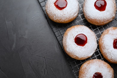 Photo of Hanukkah doughnuts with jelly and sugar powder on grey table, flat lay. Space for text