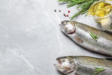 Raw cutthroat trout fish on light grey marble table, flat lay. Space for text