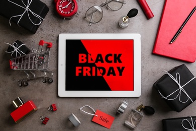 Photo of Flat lay composition with tablet, gifts and accessories on grey background. Black Friday sale
