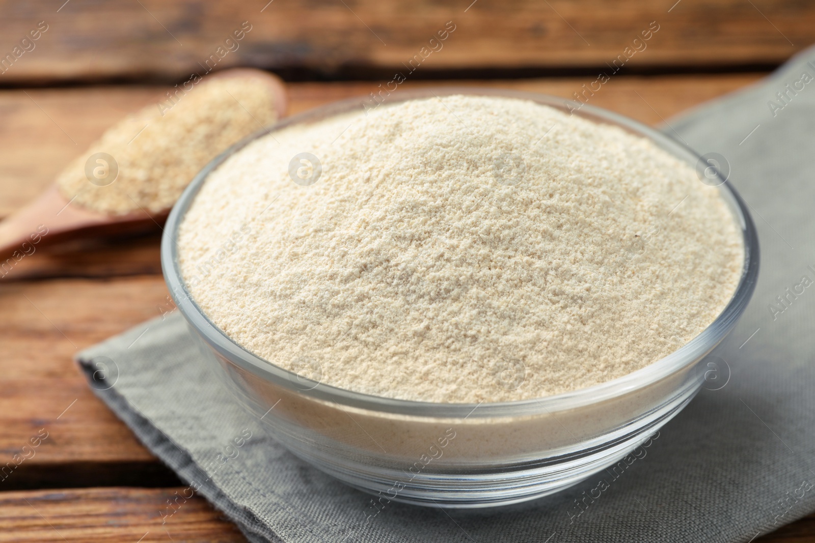 Photo of Glass bowl with quinoa flour on wooden table, closeup