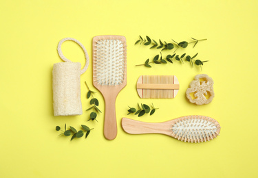 Flat lay composition with modern hair comb and brushes on yellow background