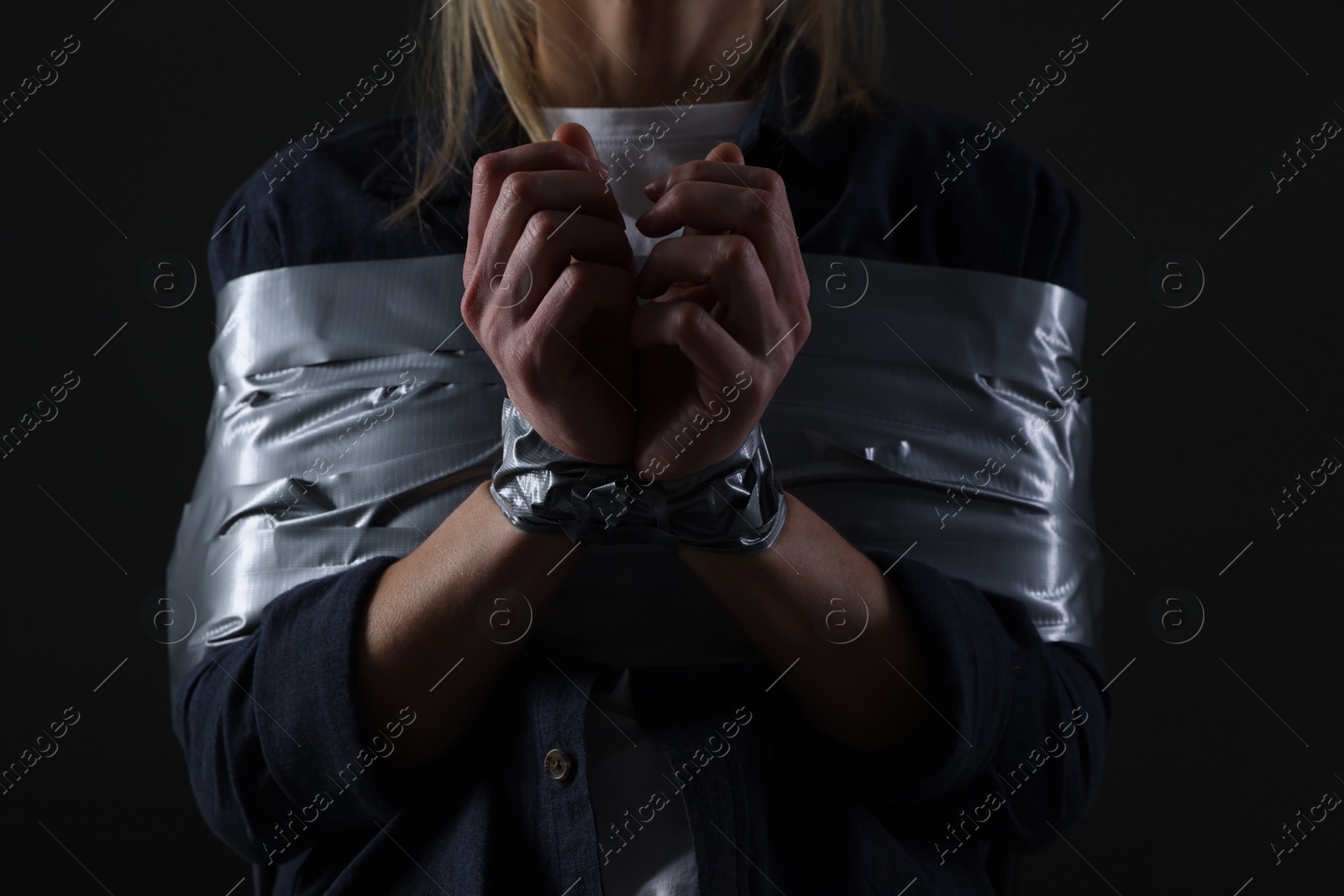 Photo of Woman taped up and taken hostage on dark background, closeup