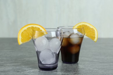 Photo of Delicious cocktail and glass with ice balls on grey table