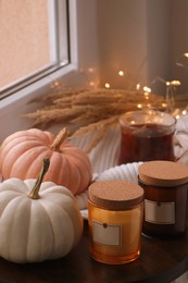 Beautiful pumpkins, tea and scented candles on window sill indoors, space for text