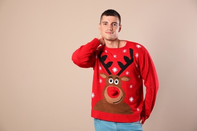 Portrait of happy man in Christmas sweater on beige background