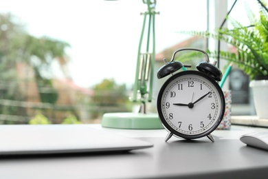 Photo of Alarm clock on table in office. Time to work