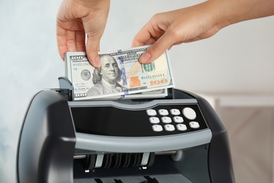 Photo of Woman putting money into counting machine indoors, closeup