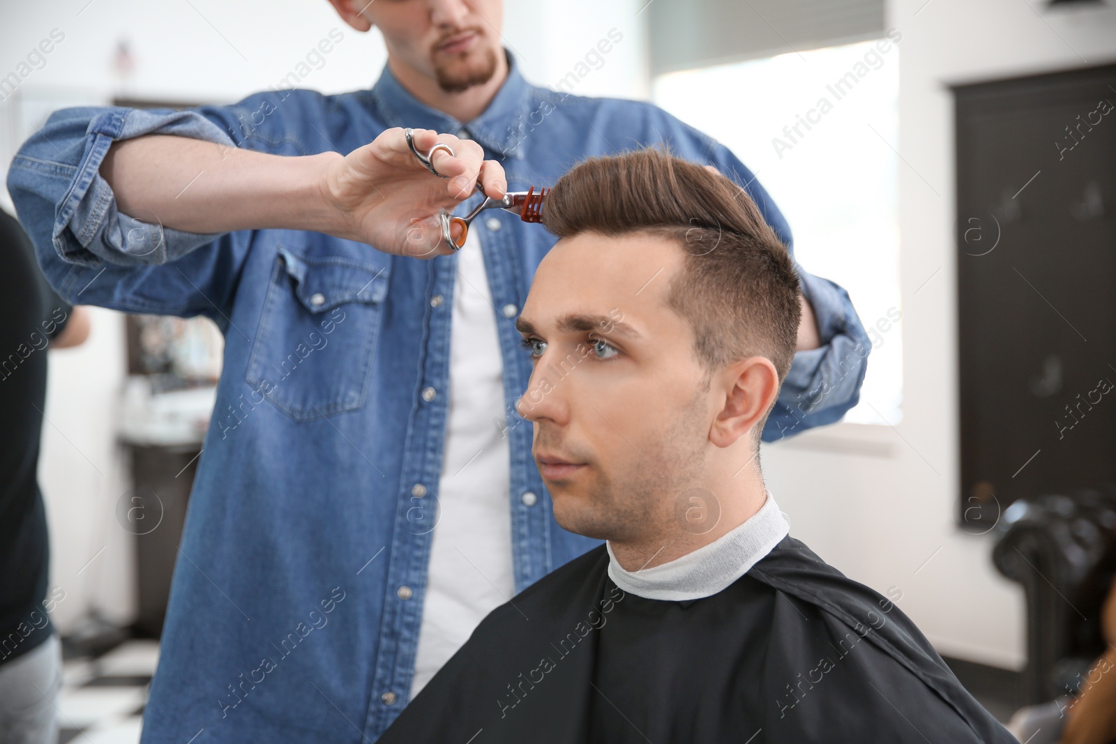 Photo of Professional barber working with client in hairdressing salon. Hipster fashion