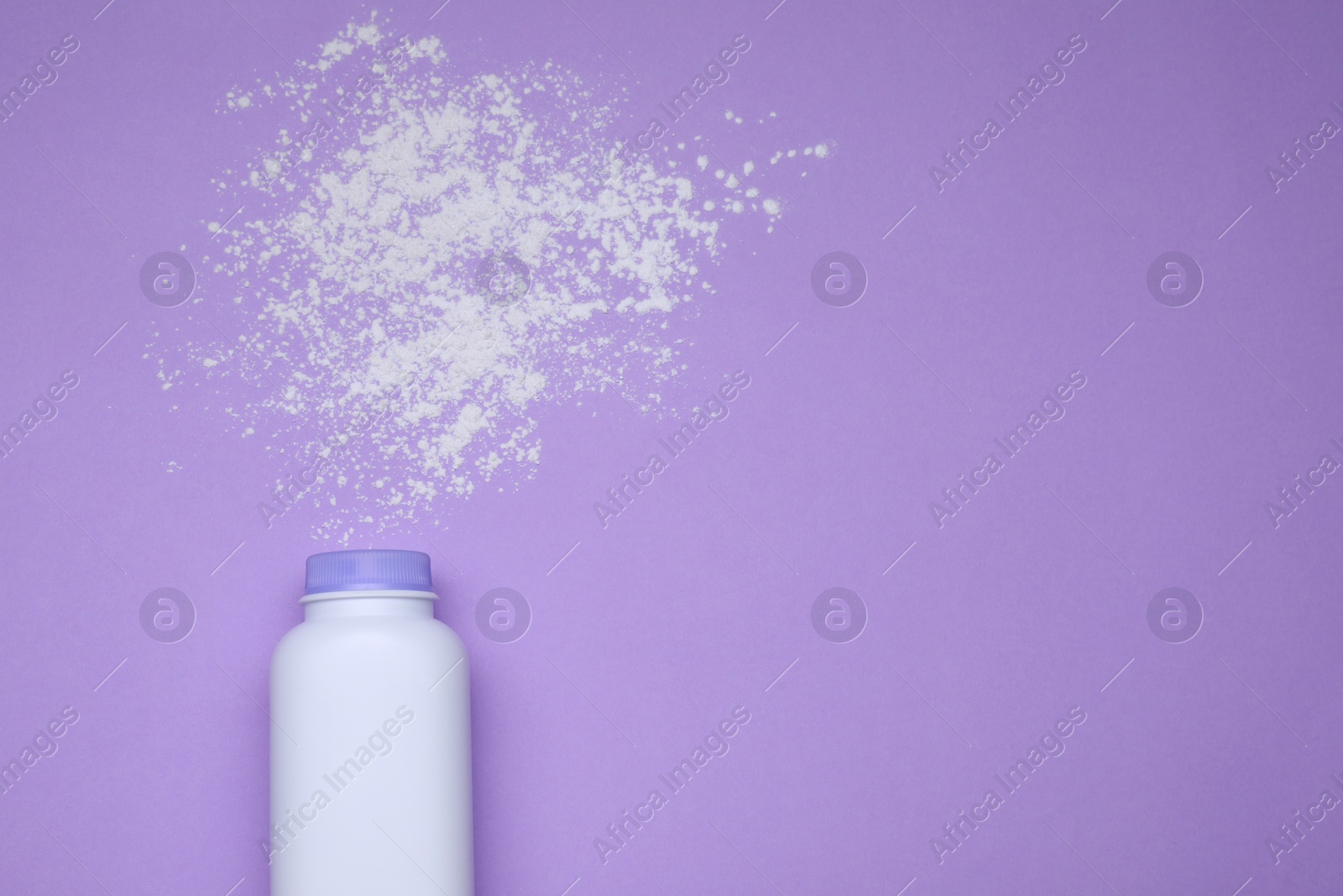 Photo of Bottle and scattered dusting powder on violet background, top view with space for text. Baby cosmetic product