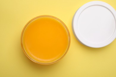 Open jar of petrolatum on yellow background, top view