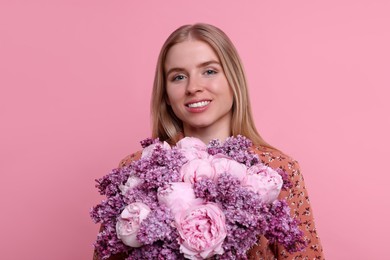 Beautiful woman with bouquet of spring flowers on pink background