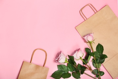 Photo of Stylish flat lay composition with shopping bags and flowers on color background