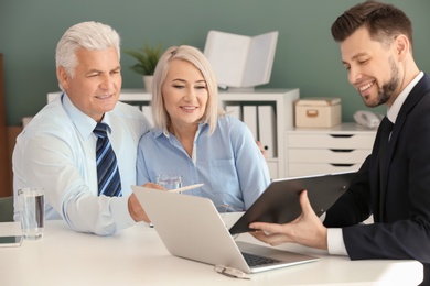 Photo of Male manager consulting mature couple in office