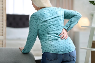 Senior woman suffering from back pain at home