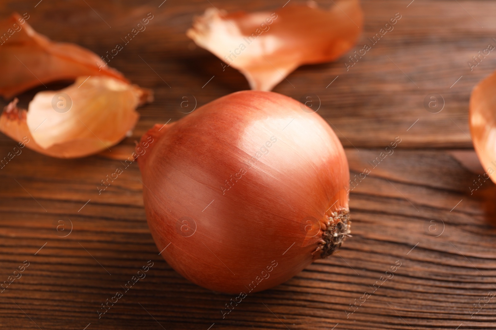 Photo of Fresh ripe onion on wooden table, closeup
