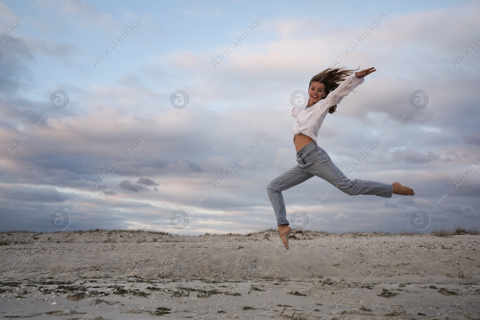 Photo of Beautiful woman dancing on beach at sunset