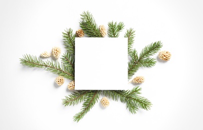 Pinecones with fir branches and blank card on white background, flat lay. Space for text
