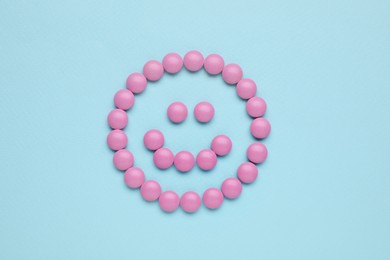 Happy emoticon made of antidepressants on light blue background, top view