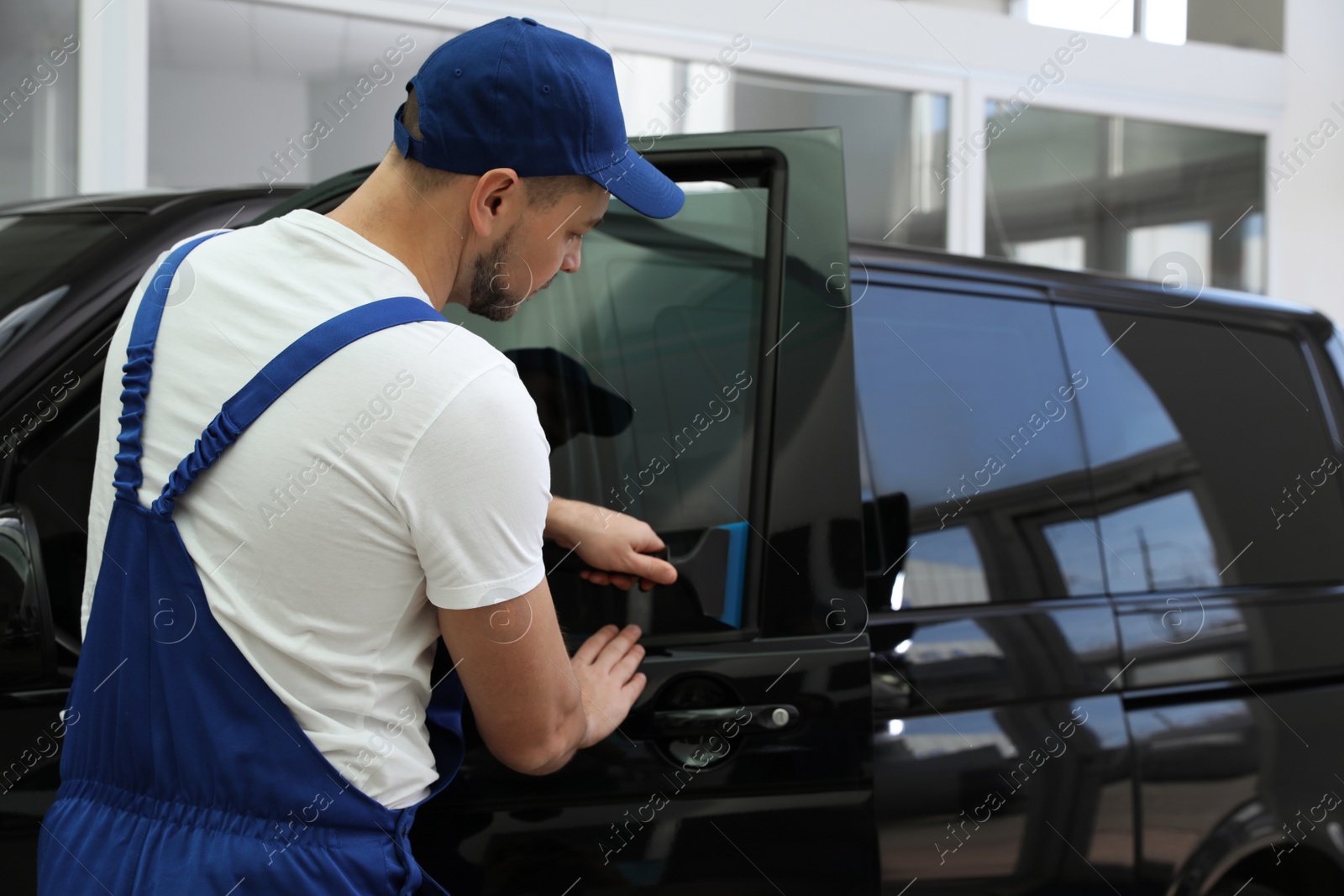 Photo of Worker tinting car window with foil in workshop