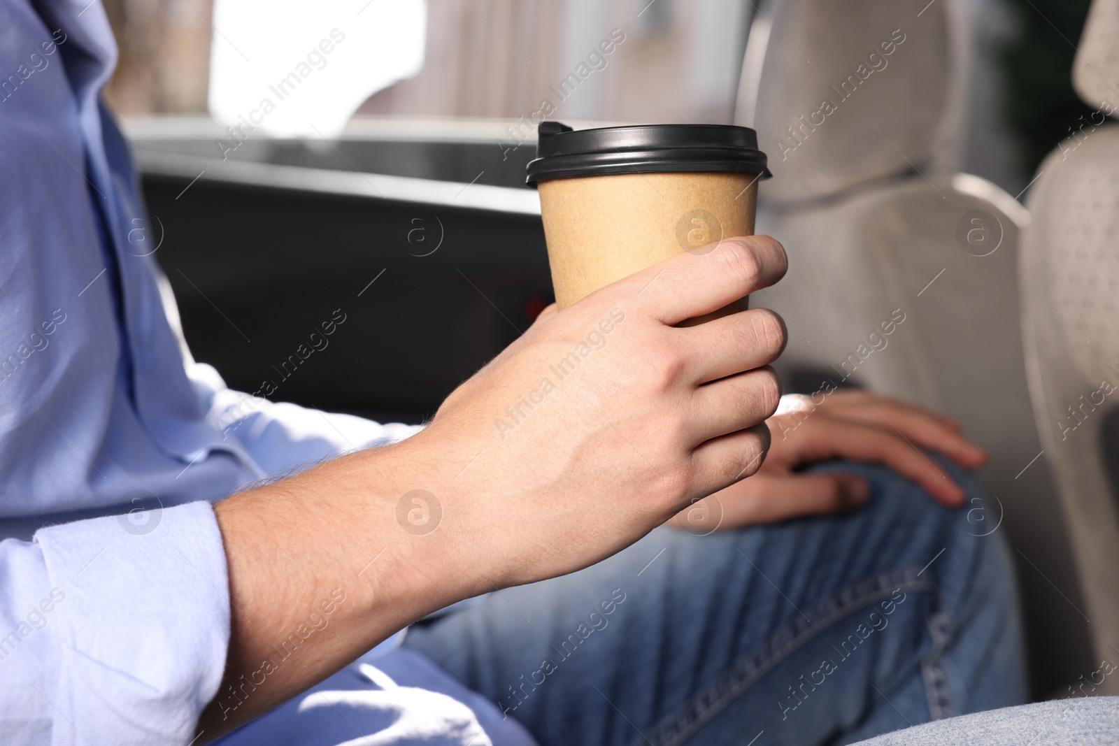 Photo of Coffee to go. Man with paper cup of drink in car, closeup